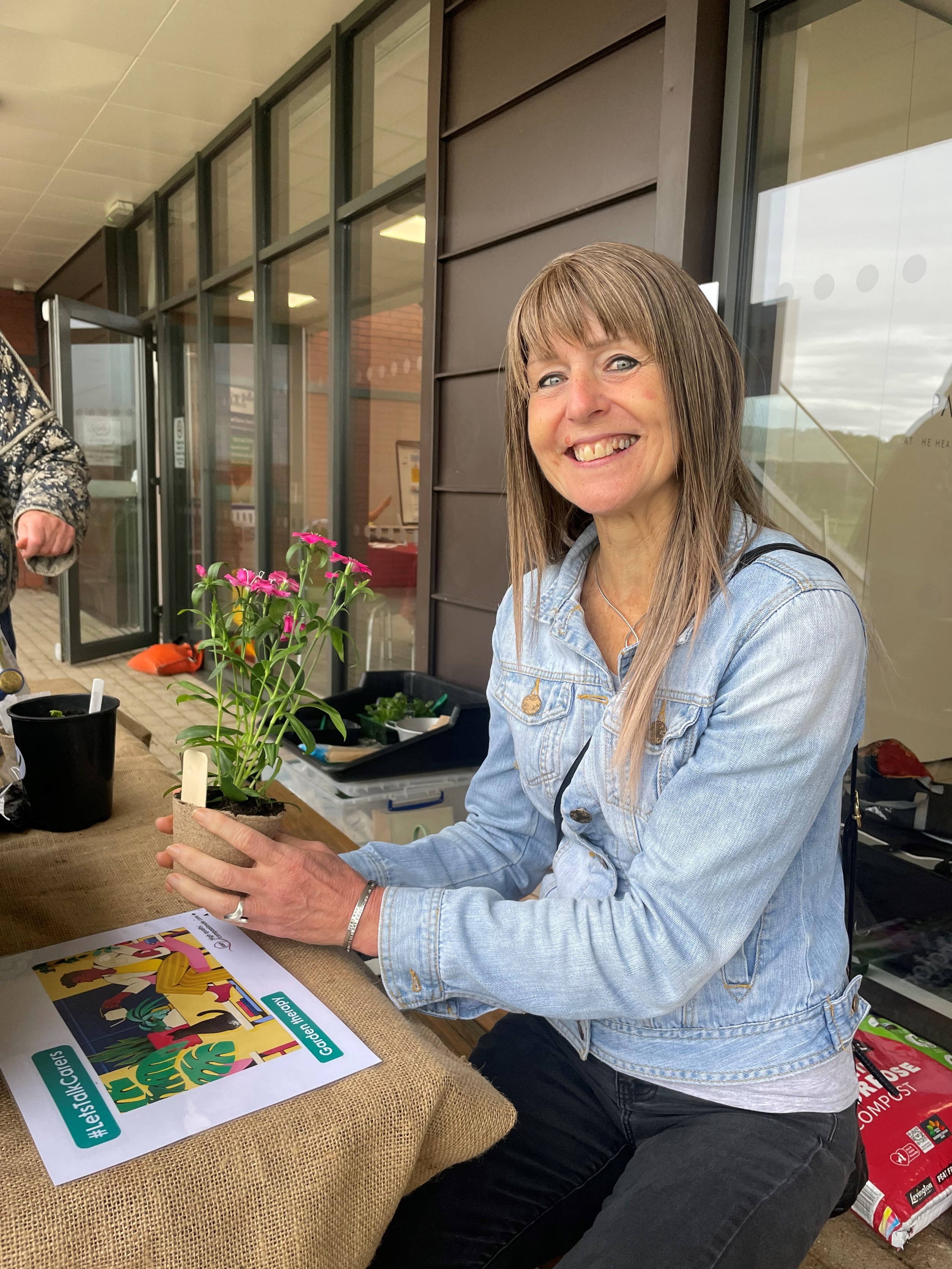 Image displays woman smiling holding a flower pot